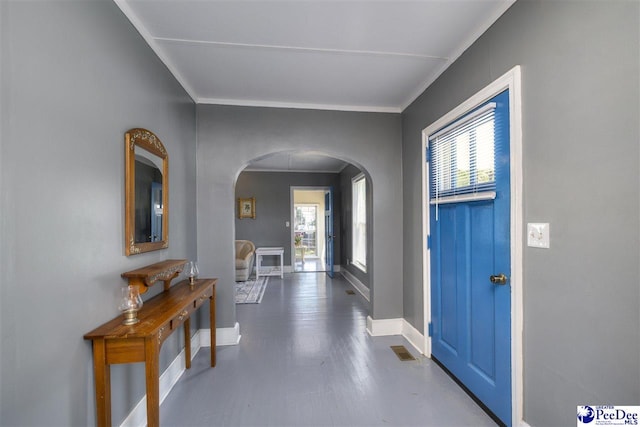 foyer with a wealth of natural light, baseboards, arched walkways, and crown molding