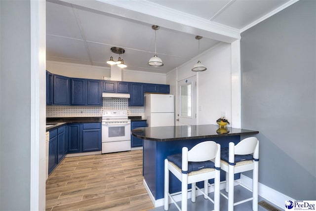 kitchen with a peninsula, dark countertops, a kitchen bar, white appliances, and blue cabinetry