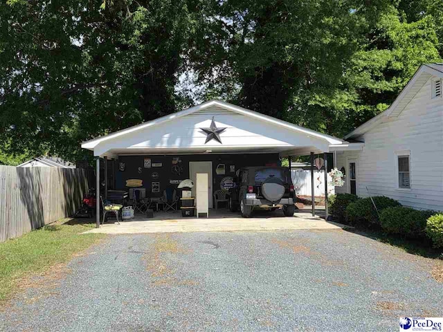 view of parking / parking lot featuring driveway and fence