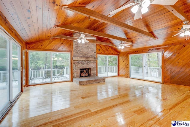 unfurnished living room with a fireplace, light hardwood / wood-style flooring, and wood walls