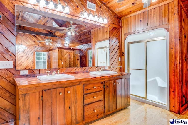 bathroom featuring a shower with shower door, wood ceiling, vaulted ceiling, wooden walls, and ceiling fan