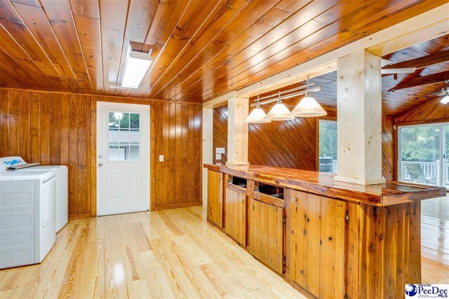 kitchen featuring wood walls, wooden ceiling, separate washer and dryer, and light wood-type flooring