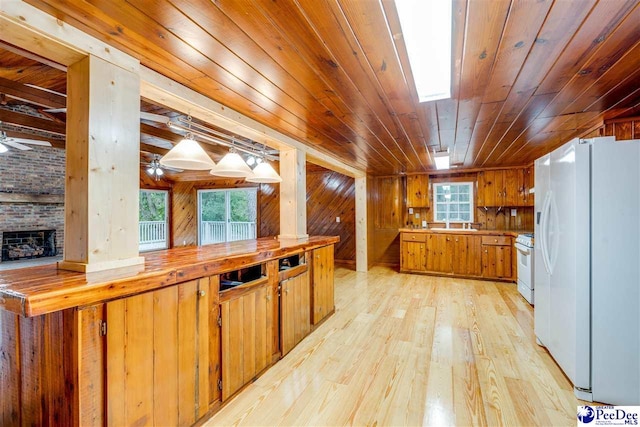 kitchen featuring pendant lighting, wood ceiling, white appliances, wooden walls, and light wood-type flooring