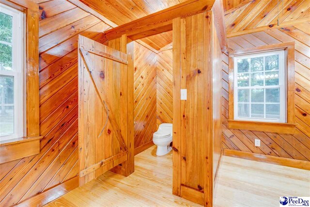 bathroom with hardwood / wood-style flooring, toilet, and wood walls