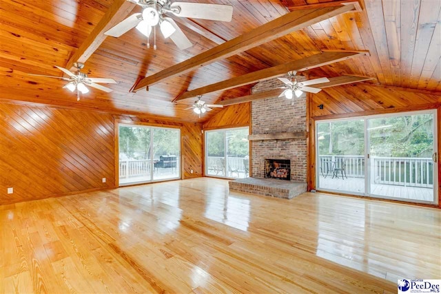 unfurnished living room with wooden walls, a brick fireplace, and light wood-type flooring