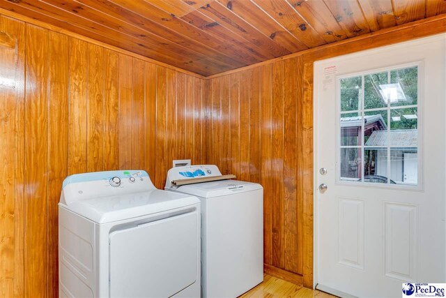 washroom featuring wood ceiling, washing machine and clothes dryer, and wood walls