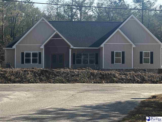 view of front facade with central AC unit and a shingled roof