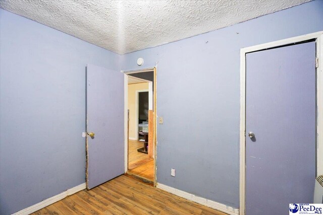 unfurnished bedroom featuring hardwood / wood-style floors and a textured ceiling