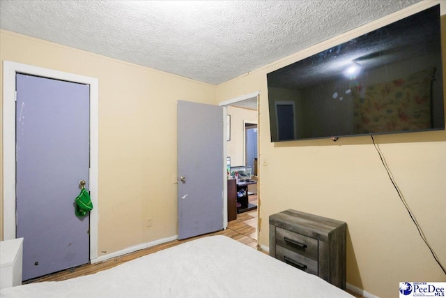 bedroom with light hardwood / wood-style floors and a textured ceiling