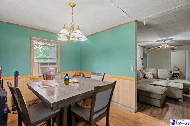 dining area featuring an inviting chandelier, hardwood / wood-style floors, wooden walls, and a textured ceiling