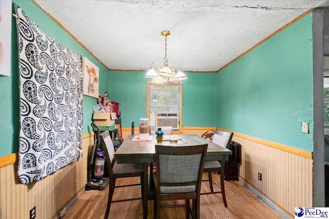 dining space with an inviting chandelier, a textured ceiling, light hardwood / wood-style flooring, and cooling unit