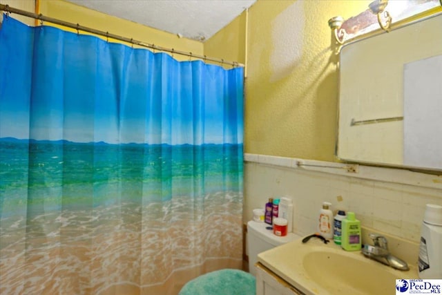 bathroom featuring tile walls, a shower with shower curtain, vanity, a textured ceiling, and toilet