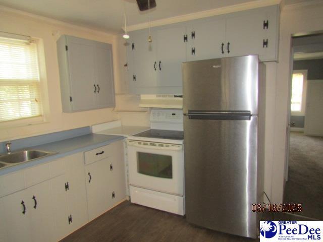 kitchen featuring white cabinetry, a sink, freestanding refrigerator, under cabinet range hood, and electric stove