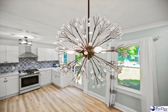 1314 Sewanee Ave, Florence, SC 29501 - kitchen with range with gas stovetop, wall chimney range hood, a chandelier, and white cabinets