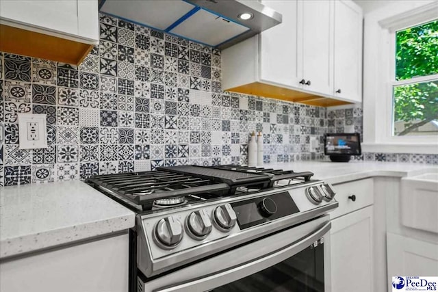 1314 Sewanee Ave, Florence, SC 29501 - kitchen with stainless steel gas range oven, exhaust hood, white cabinetry, and decorative backsplash