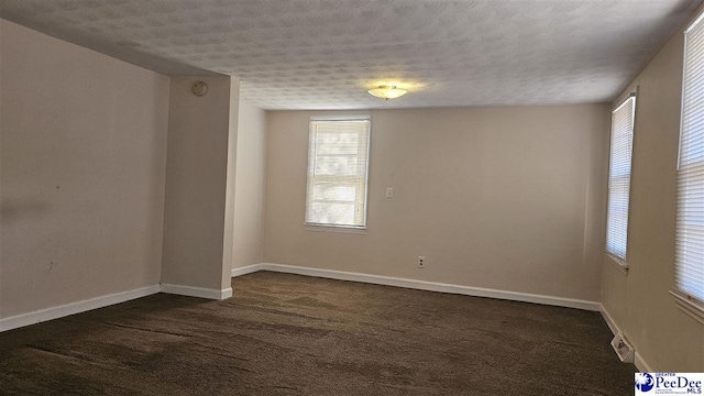 carpeted empty room featuring a textured ceiling