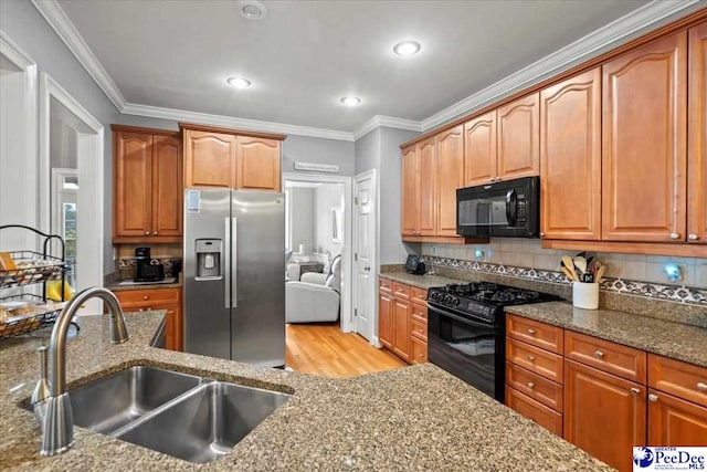 kitchen featuring sink, crown molding, light stone counters, tasteful backsplash, and black appliances
