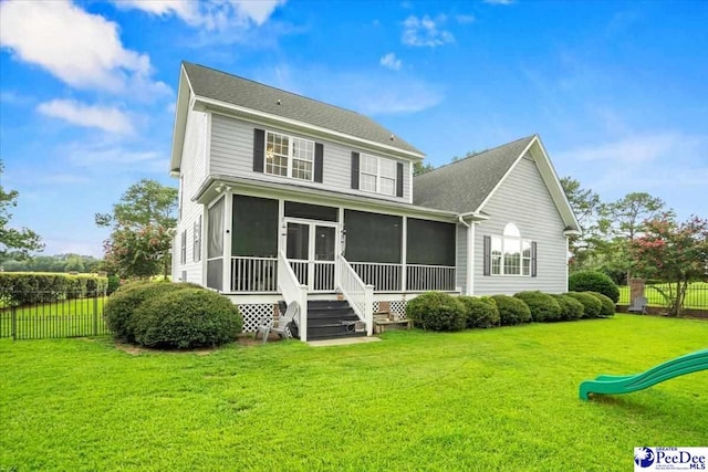 rear view of property with a yard, a playground, and a sunroom