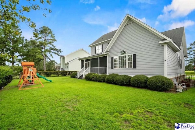 rear view of house with a yard, a playground, and a sunroom