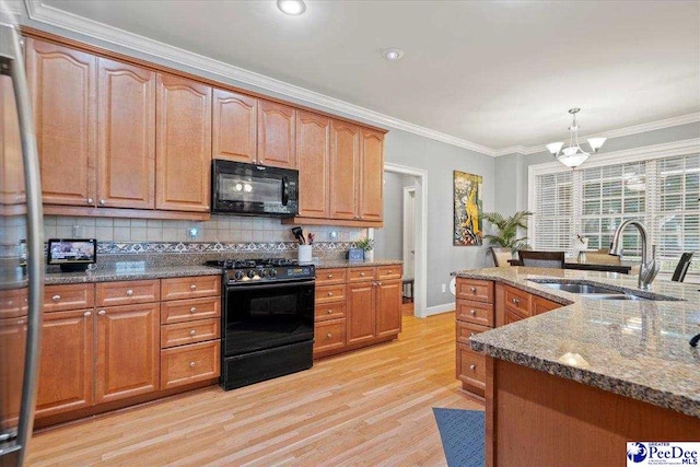 kitchen featuring decorative light fixtures, sink, dark stone countertops, black appliances, and crown molding