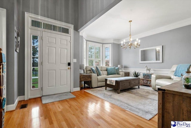 entrance foyer with ornamental molding, a chandelier, and light hardwood / wood-style floors