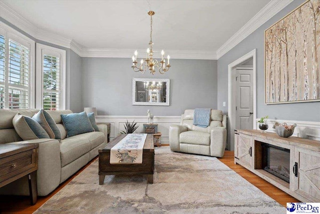 living room featuring ornamental molding, a notable chandelier, and light wood-type flooring