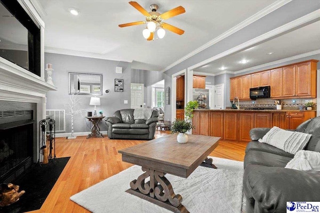 living room with crown molding, ceiling fan, and light wood-type flooring