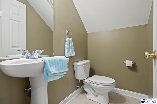 bathroom with lofted ceiling, tile patterned floors, and toilet