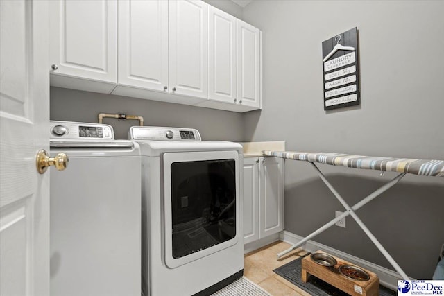 laundry area with cabinets, washer and dryer, and light tile patterned floors
