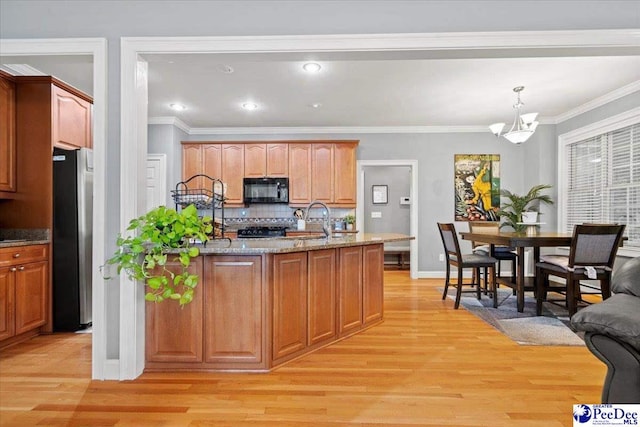 kitchen with pendant lighting, sink, stainless steel fridge, and light hardwood / wood-style floors