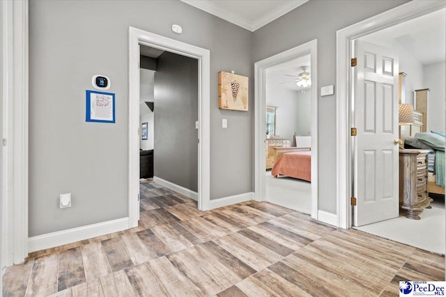 corridor with ornamental molding and light wood-type flooring