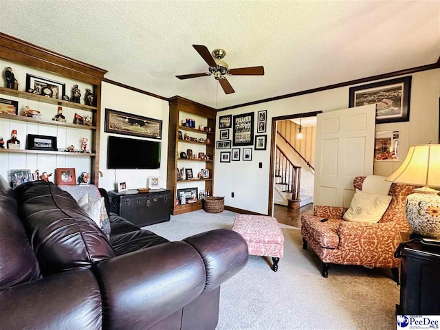 carpeted living room with a ceiling fan, crown molding, stairway, built in shelves, and baseboards