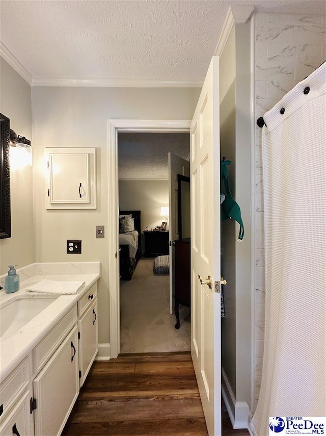 ensuite bathroom featuring wood finished floors, crown molding, a textured ceiling, vanity, and curtained shower