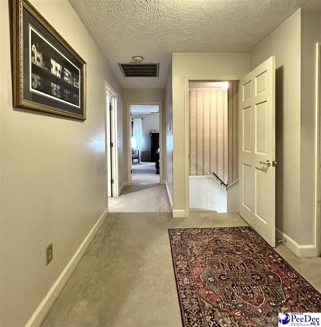 1217 Hillside Dr, Dillon, SC 29536 - hallway featuring an upstairs landing, carpet flooring, baseboards, and a textured ceiling