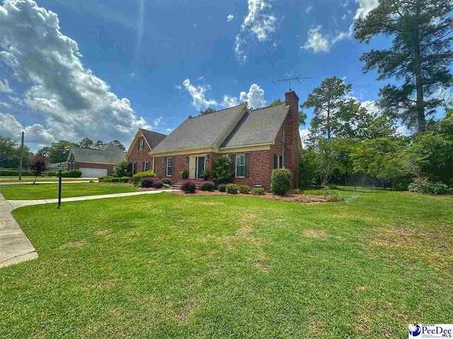 1217 Hillside Dr, Dillon, SC 29536 - view of front of home with a front yard, a chimney, brick siding, and driveway
