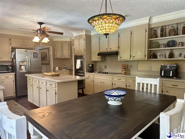 kitchen with black appliances, under cabinet range hood, crown molding, a textured ceiling, and a kitchen island