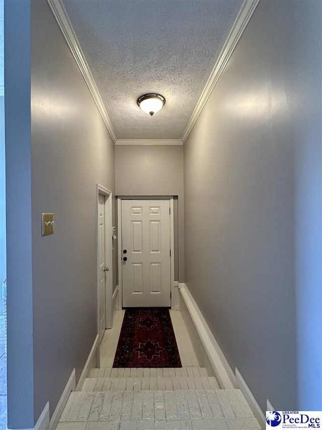 entryway with a textured ceiling, ornamental molding, and baseboards