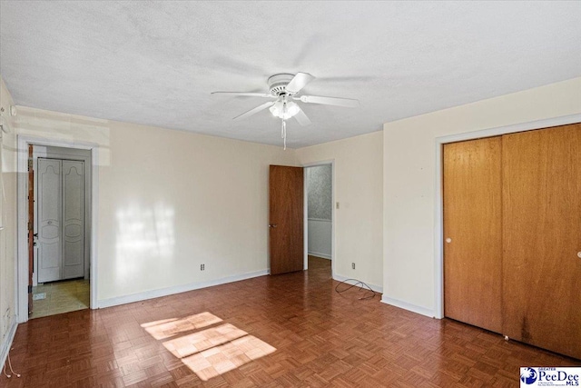 unfurnished bedroom featuring ceiling fan, parquet flooring, a closet, and a textured ceiling