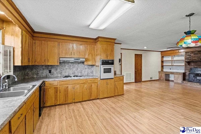 kitchen with sink, backsplash, hanging light fixtures, light hardwood / wood-style floors, and white appliances