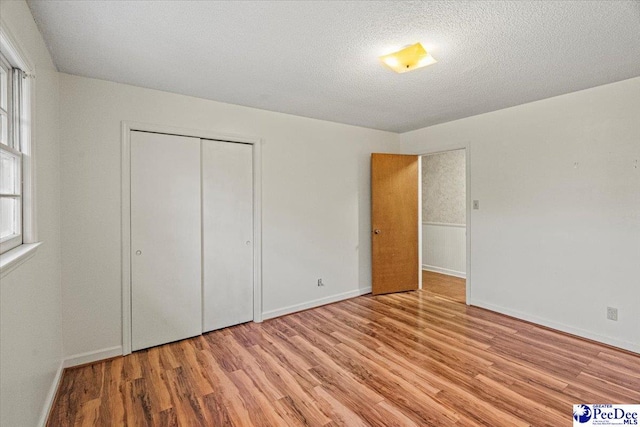 unfurnished bedroom featuring a closet, a textured ceiling, and light hardwood / wood-style flooring