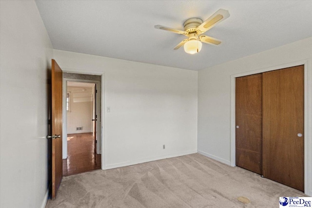 unfurnished bedroom featuring light carpet, a closet, and ceiling fan