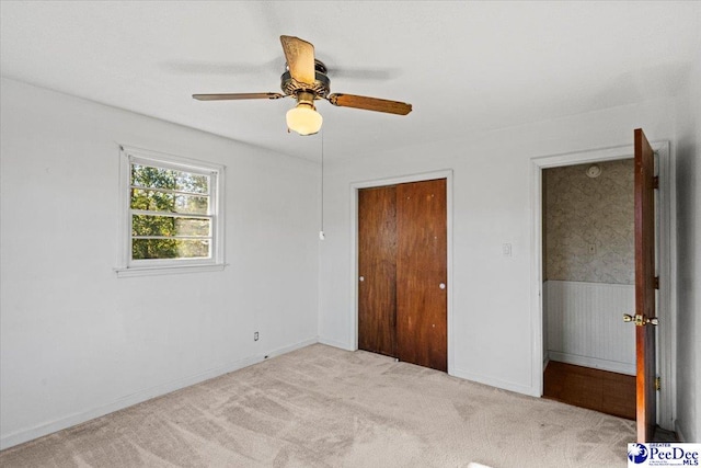 unfurnished bedroom with light carpet, ceiling fan, and a closet