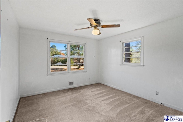 spare room with ceiling fan, light carpet, and a wealth of natural light