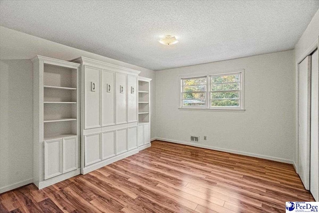 unfurnished bedroom with a closet, hardwood / wood-style floors, and a textured ceiling