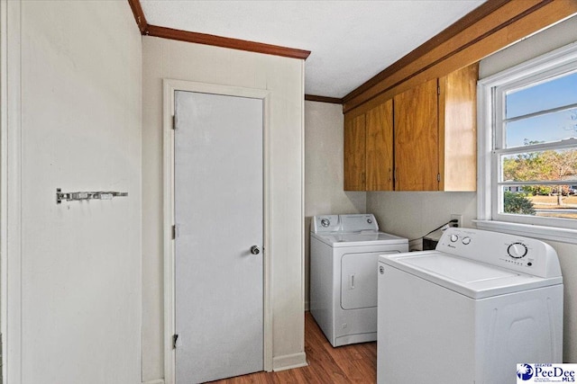 washroom featuring cabinets, ornamental molding, washing machine and dryer, and light wood-type flooring