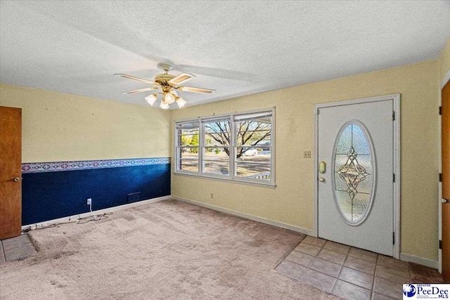 carpeted entrance foyer featuring ceiling fan and a textured ceiling