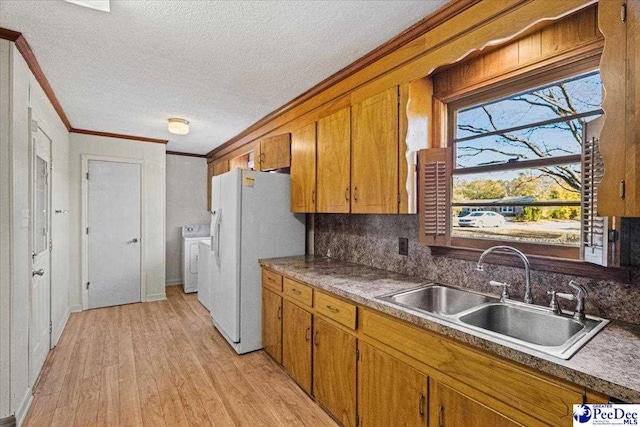 kitchen with sink, light hardwood / wood-style flooring, ornamental molding, white fridge with ice dispenser, and washer and clothes dryer