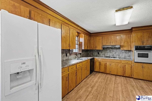 kitchen featuring sink, white appliances, backsplash, light hardwood / wood-style floors, and a textured ceiling