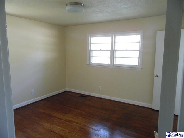 spare room with dark hardwood / wood-style flooring and a textured ceiling