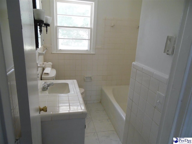 bathroom with toilet, sink, tile walls, and a bathtub